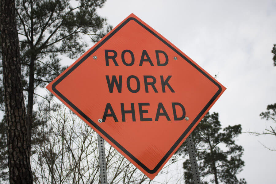 orange road work sign warning against construction site accidents