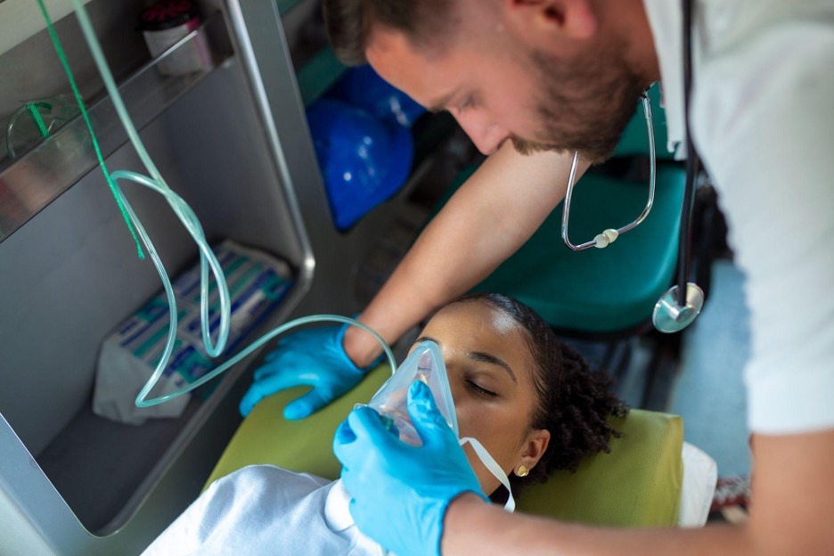 ambulance driver puts mask on patient