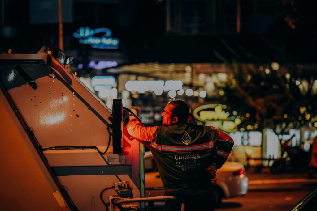 a man riding behind a garbage truck