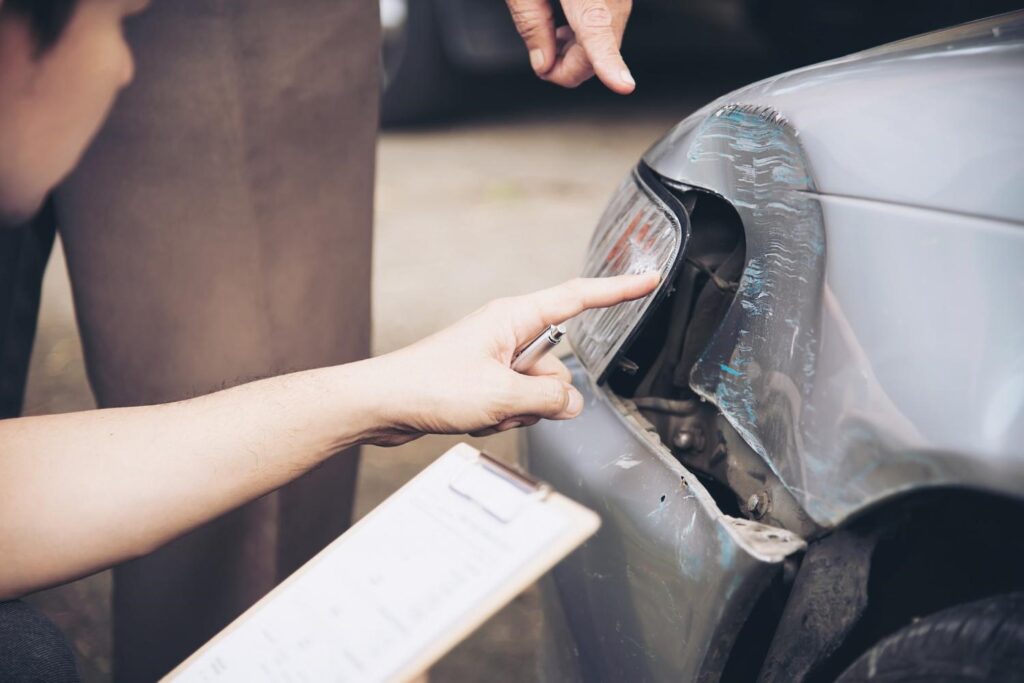 a person checking the damaged area of the car accident